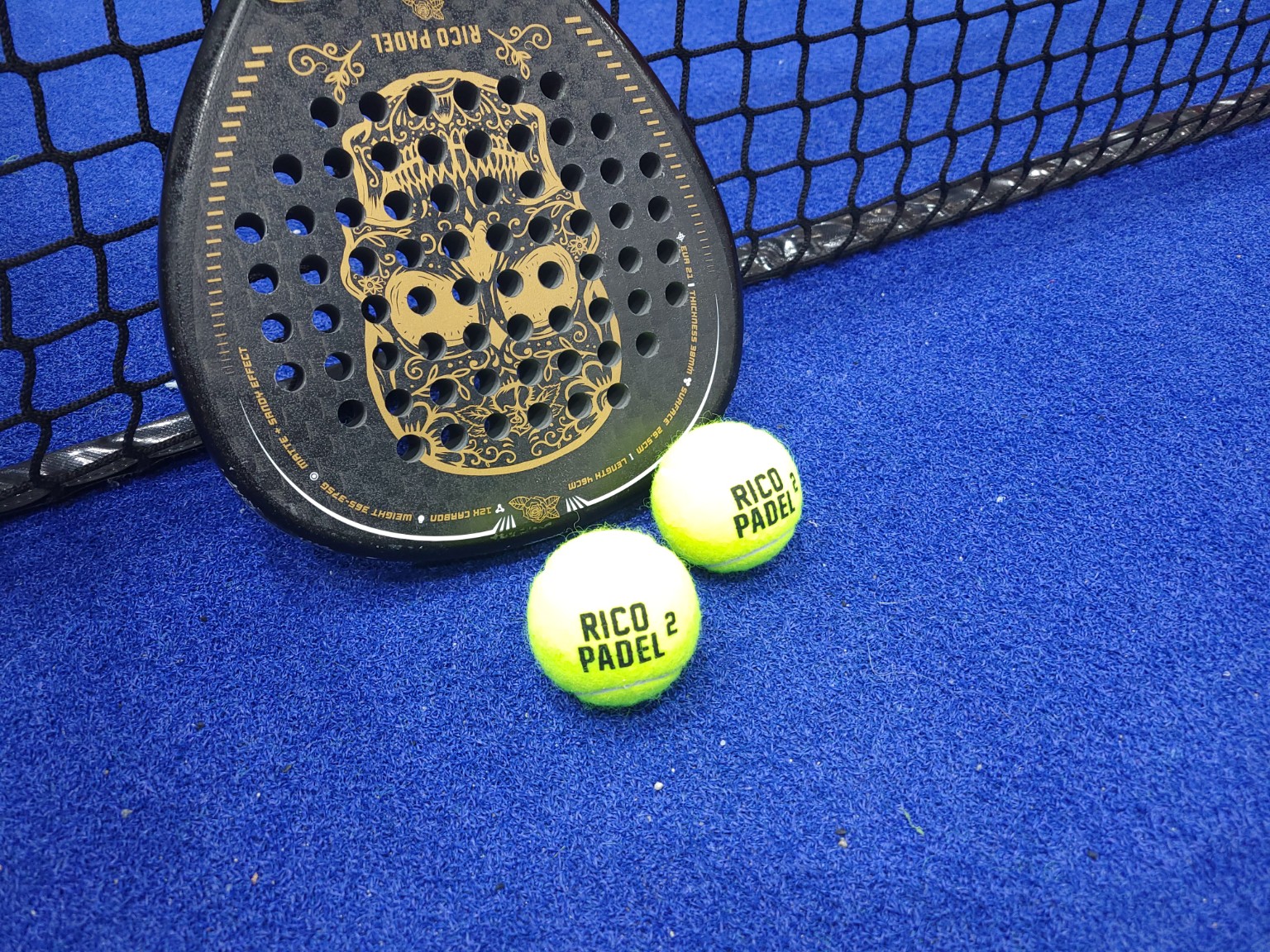 RicoPadel balls on a blue padel court